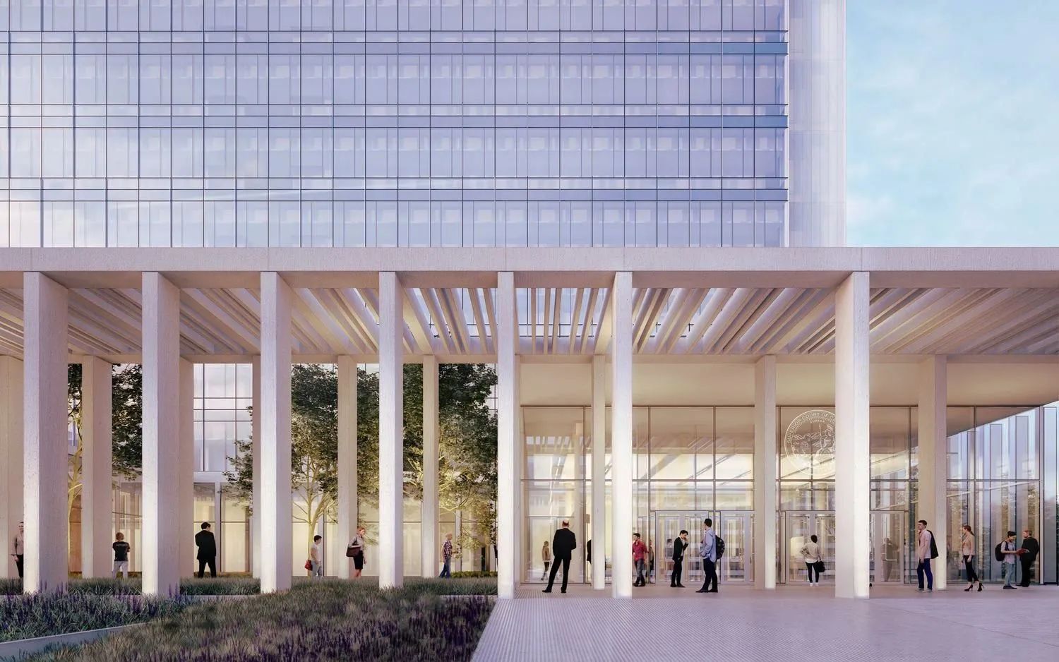 Modern courthouse-style building with tall white columns, glass walls, and people walking through a spacious open-air entrance plaza at dusk.