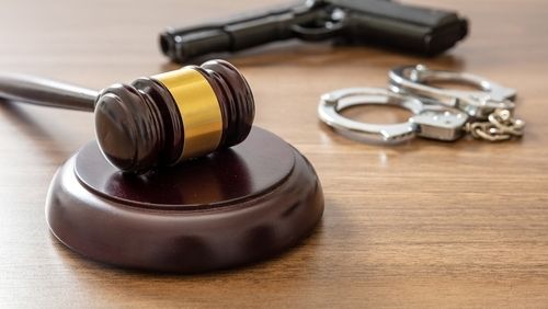 Judge gavel and handgun on lawyer office desk. Crime, murder punishment concept. Wooden courthouse table, close up view